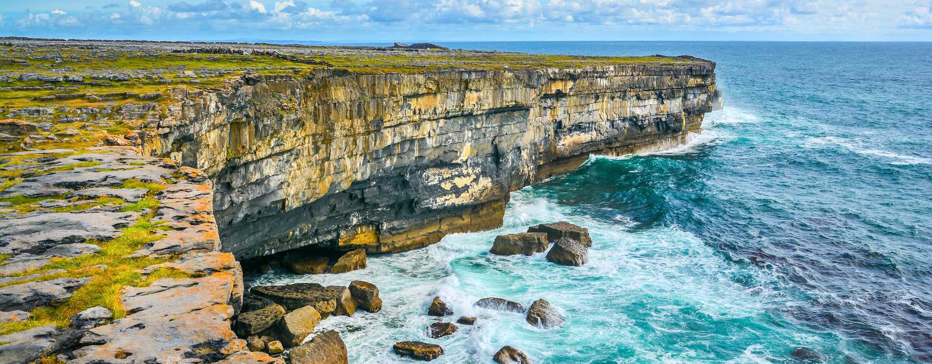 Aran Islands natural landscapes – Book the best local guided tours, ferry routes, and e-bike hires from Dublin, Galway, or Doolin in 2026 Scenic view of travelers cycling along the coastal stone-walled paths of Inishmore with panoramic views of the Atlantic Ocean – Definitive travel guide for Aran Islands excursions in 2026